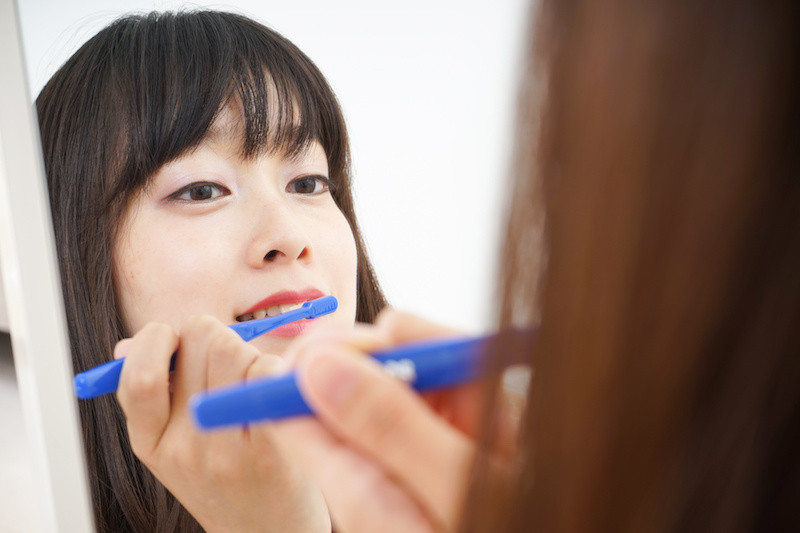 鏡を見ながら歯を磨いている女性